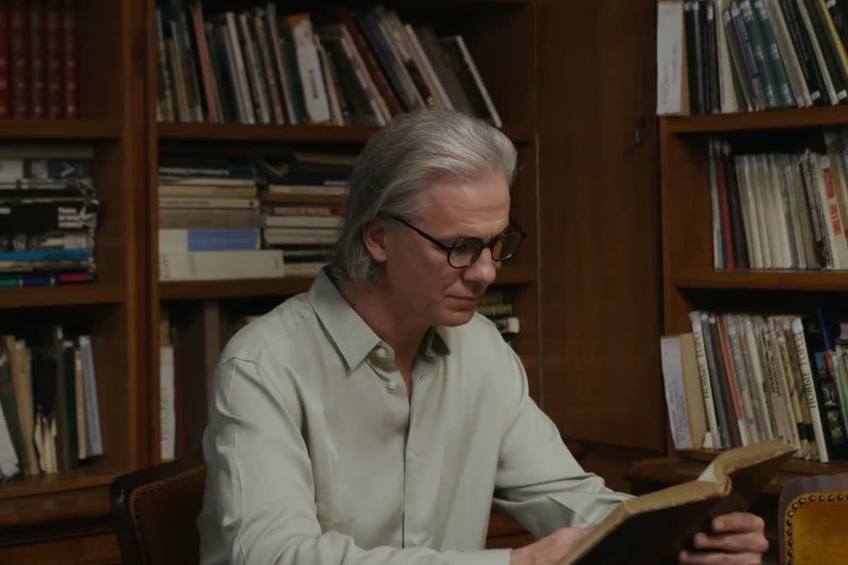 Hombre mayor leyendo un libro en una biblioteca de madera